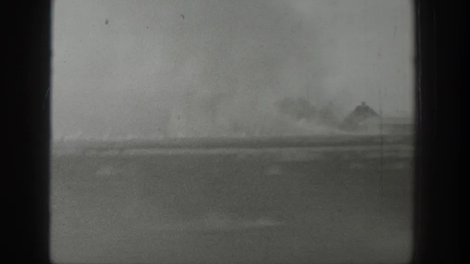 1939 Wyoming 8mm frame showing a soft rural landscape through dark bus-window bars during travel.