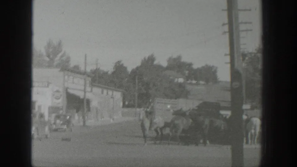 1939 Wyoming rural street scene with horses, a mounted rider, bystanders, low buildings, and utility poles.