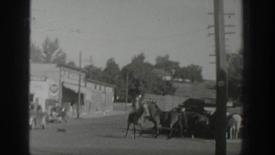1939 Wyoming street view with a rider on horseback, several horses, roadside buildings, trees, and utility poles.