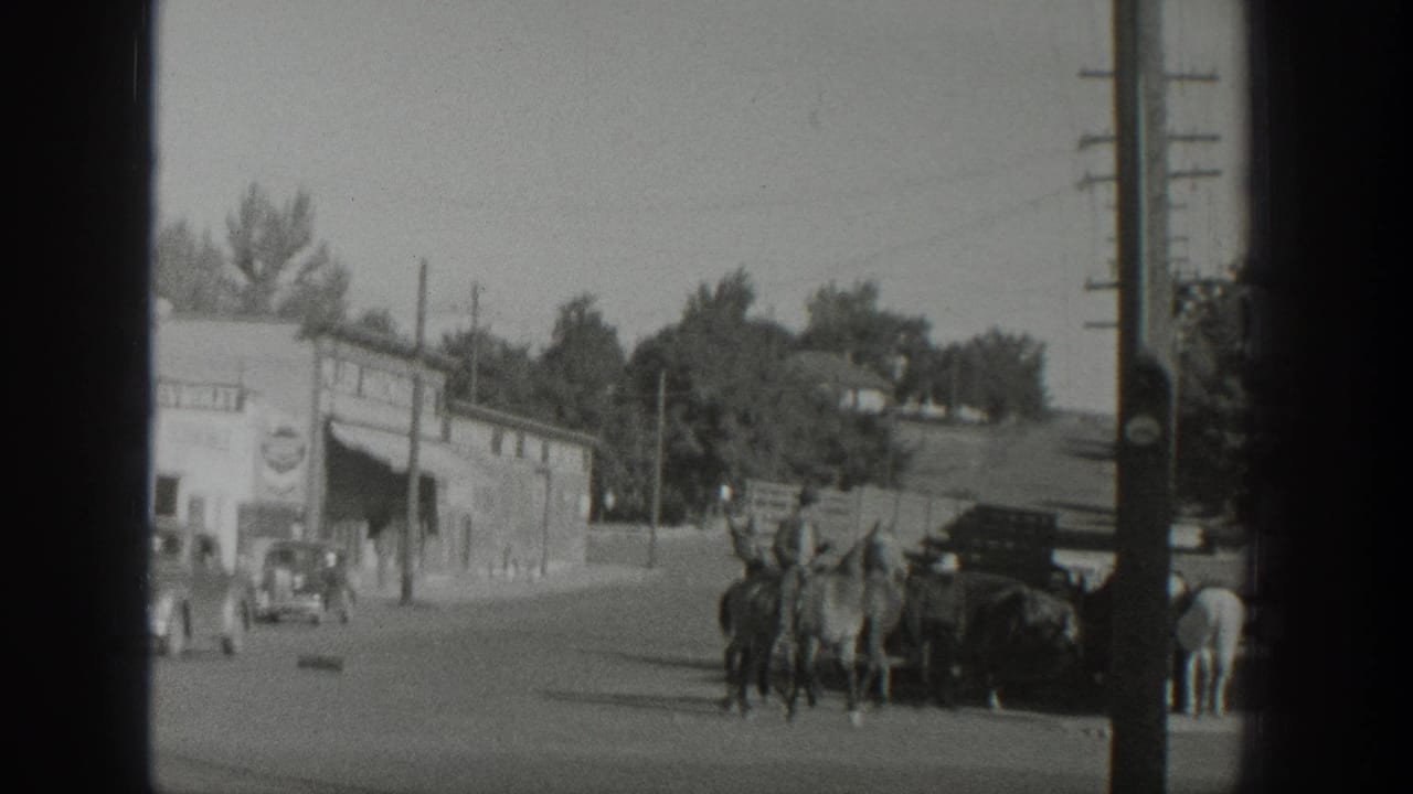 In 1939 Wyoming footage, a rider appears to lead several horses past storefronts, utility poles, pedestrians, and parked early automobiles.
