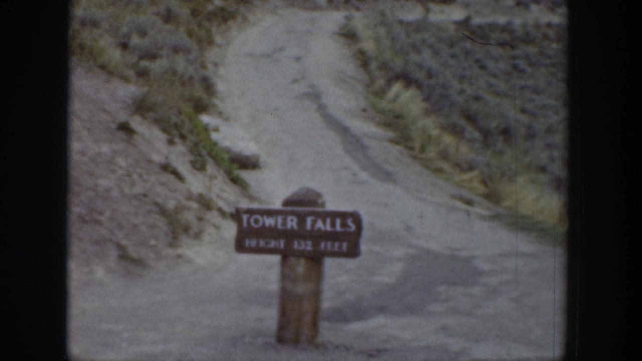 Tower Falls sign centered below a dirt path cutting through rocky terrain.