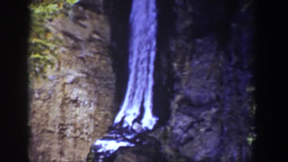 1939 Wyoming 8mm frame showing the lower waterfall column descending beside textured rock toward a darker pool or base area.