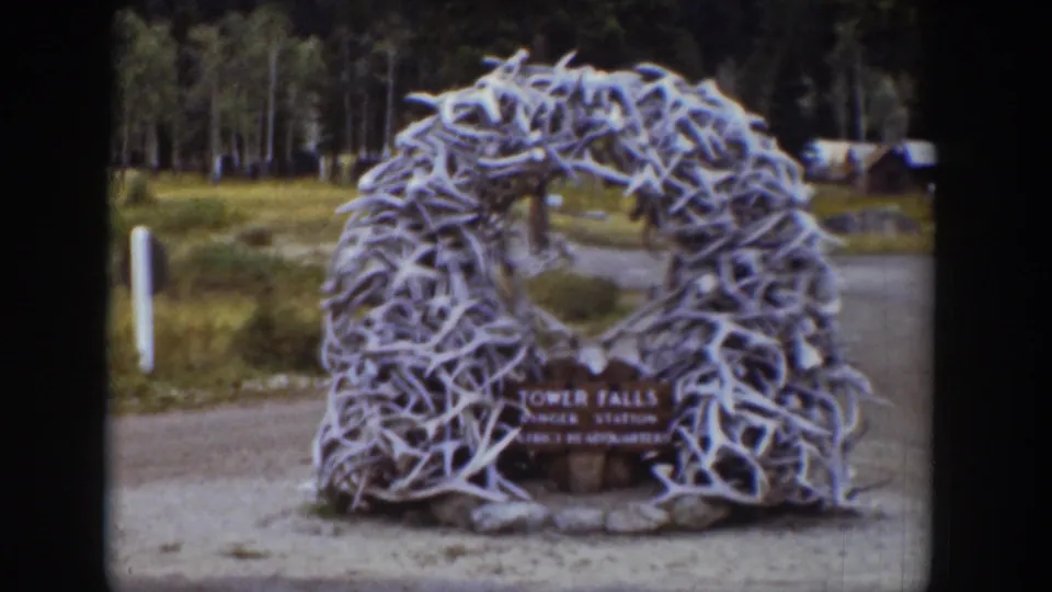 The antler-built entrance arch and Tower Falls Ranger Station sign appear centered in a 1939 Wyoming home-movie view.