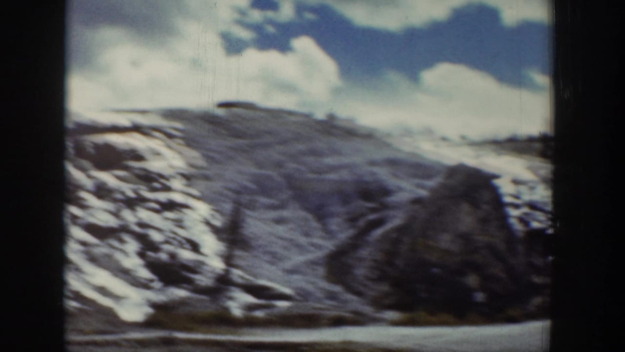 Snow-dusted hillside with road and large rock near the right edge.
