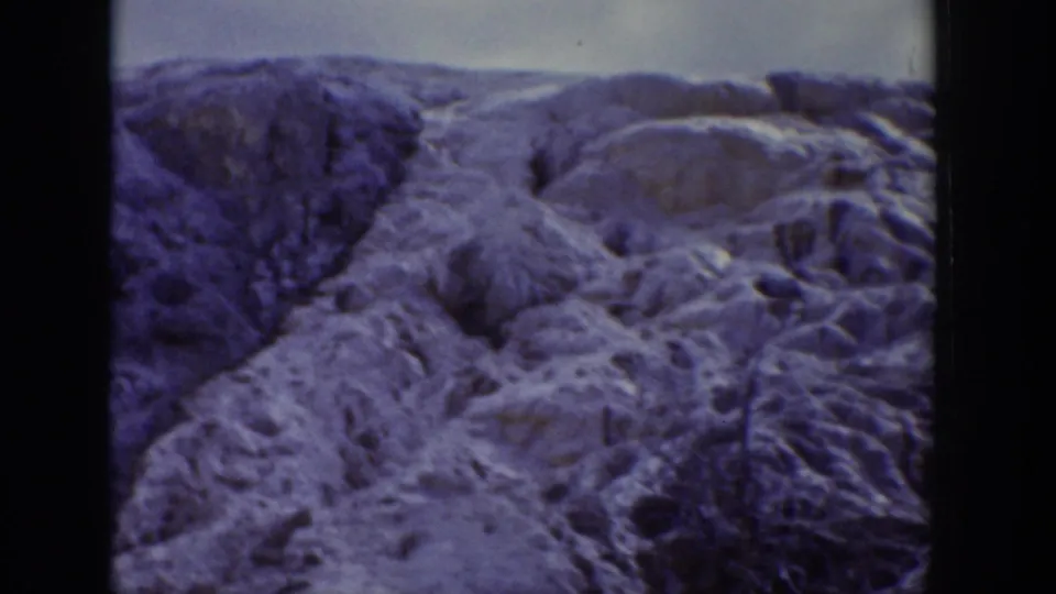 1939 Wyoming 8mm frame showing snow-covered rock formations and sparse trees in a mountain landscape.