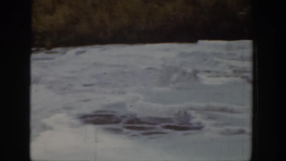 1939 Wyoming 8mm frame showing a frozen river surface with uneven ice, snow, and darker exposed water patches.