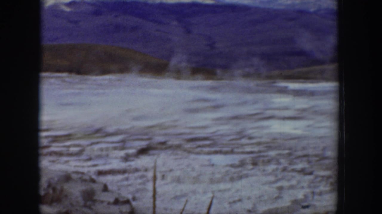 Frozen flat landscape with mountains in the distance and a dark ridge line.