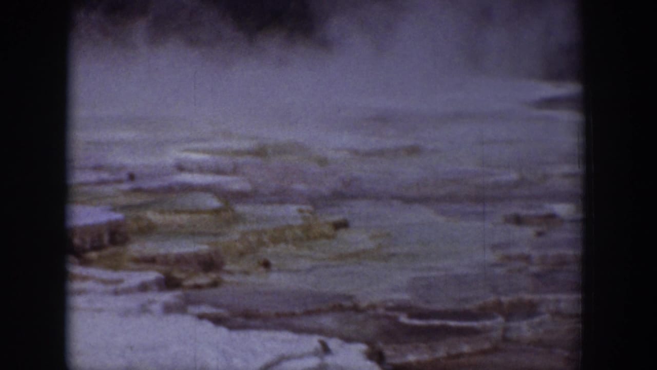 1939 Wyoming 8mm view of steaming geothermal terraces with pale mineral deposits and soft film grain.