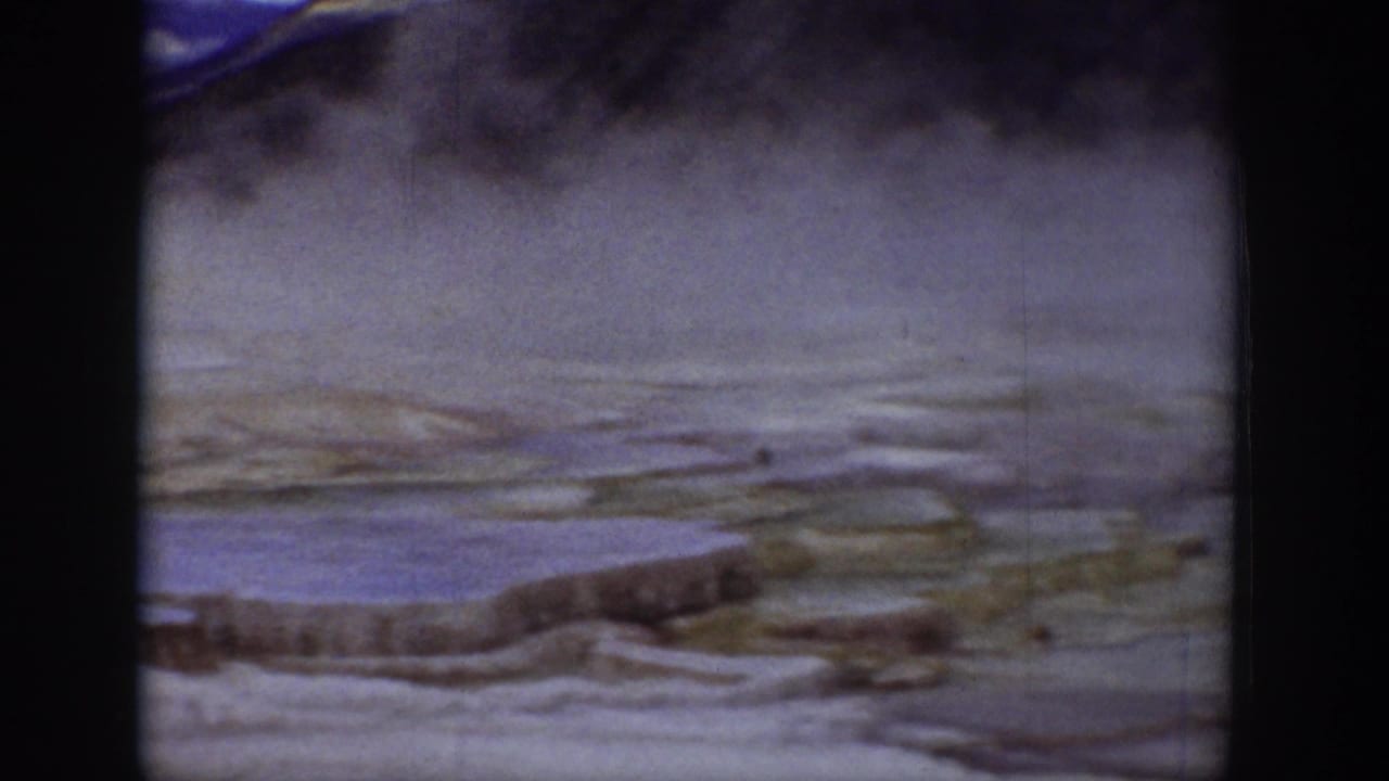 Steaming terraces and mineral shelves viewed from a distance.