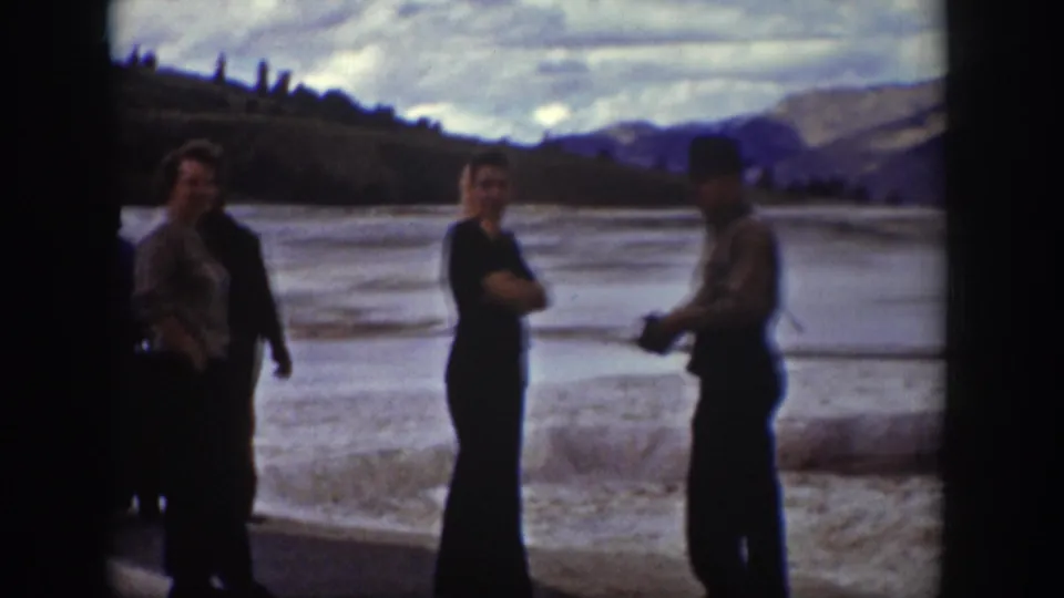 Adults in period clothing stand by a river in Wyoming, with mountains behind them in 1939 home-movie footage.