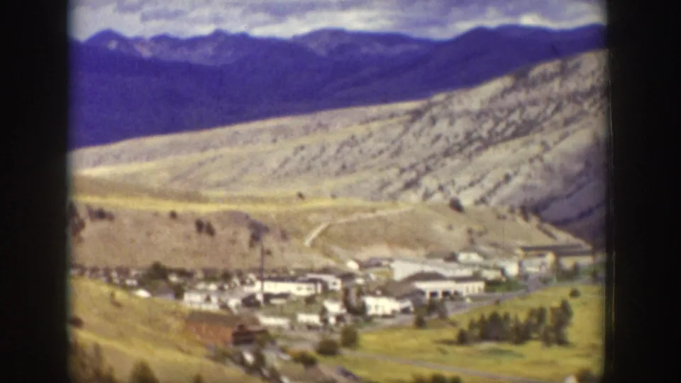 Wyoming mountain valley view with pale slopes, distant peaks, and a small settlement or facility below.