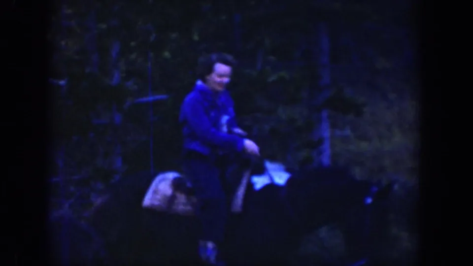 Dark 1939 Wyoming home-movie frame showing a mounted rider in a blue jacket near trees, likely later in the same outdoor outing.