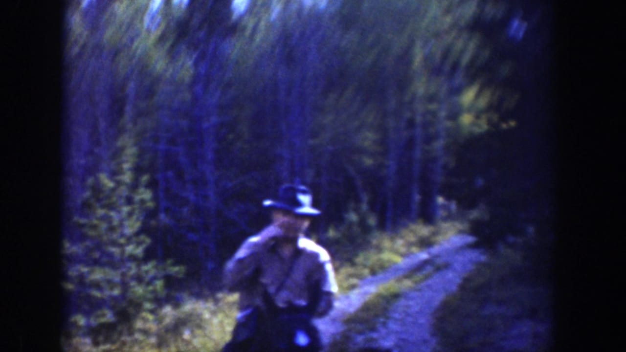 1939 Wyoming home-movie frame showing a rider in a cowboy hat on horseback beside a narrow forest trail.