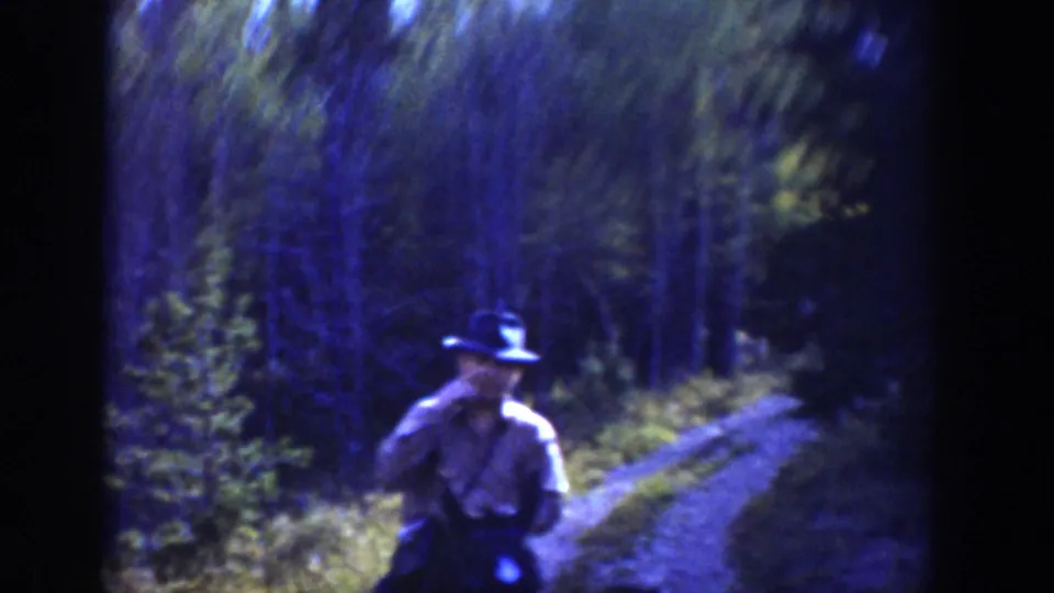 1939 Wyoming home-movie frame showing a rider in a cowboy hat on horseback beside a narrow forest trail.
