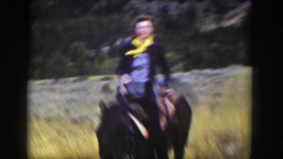 1939 Wyoming frame of a rider wearing a yellow scarf on horseback in a grassy forest setting.