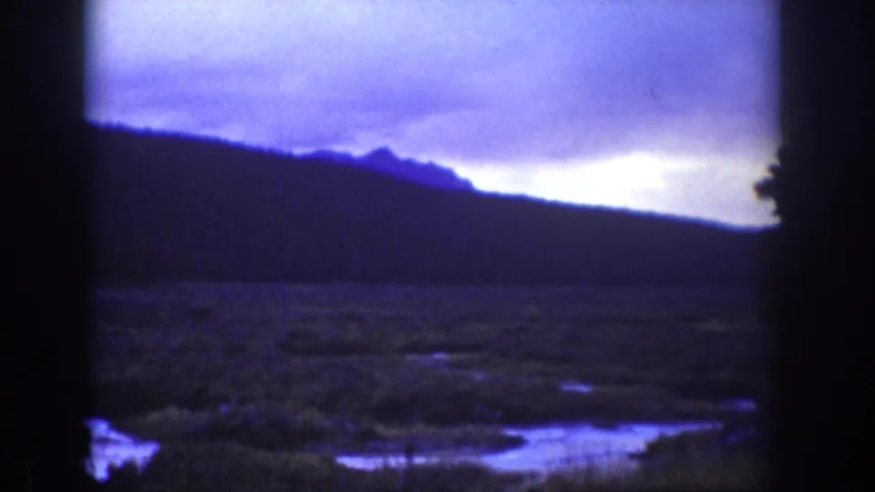 Second Wyoming 1939 landscape frame with dark hills, pale cloudy sky, wet lowland areas, and visible 8mm frame borders.