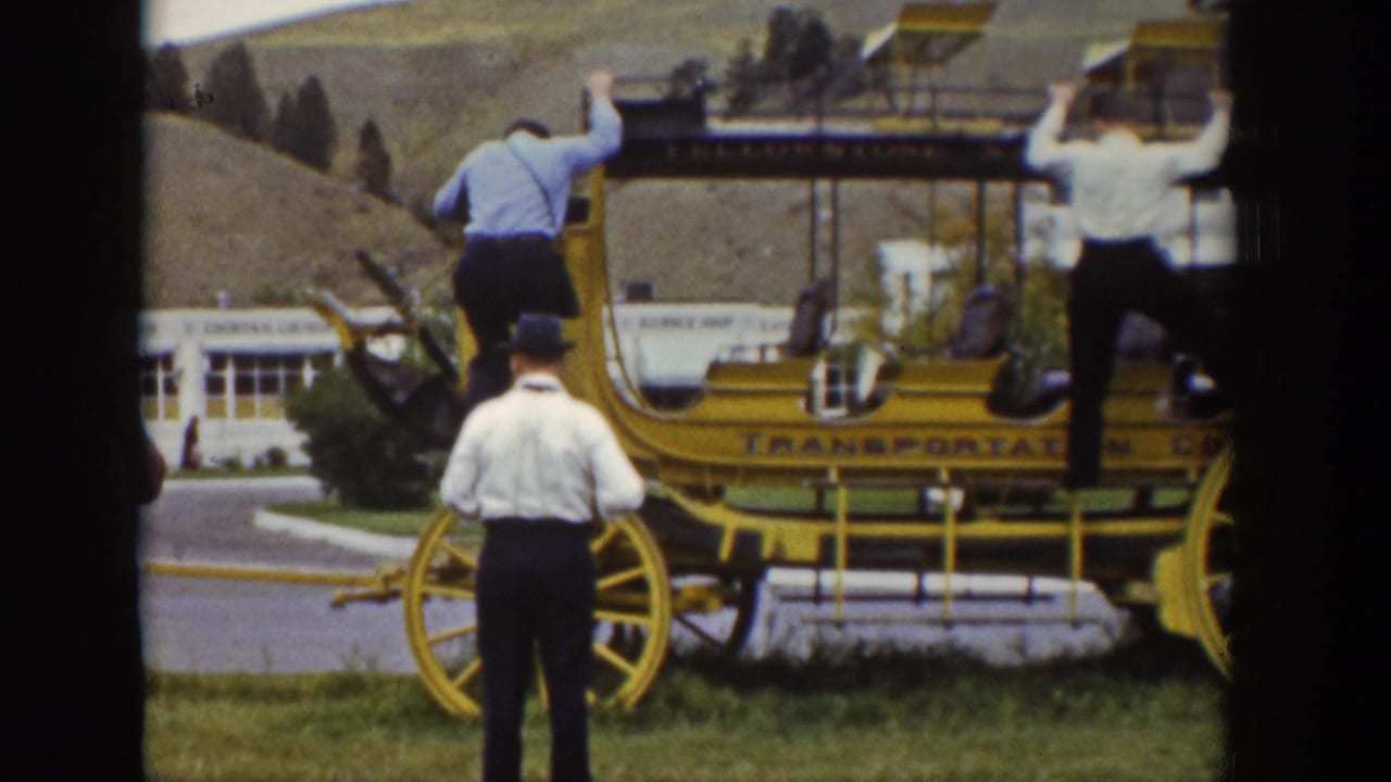 Two men climb onto a yellow wagon while another man stands facing it.