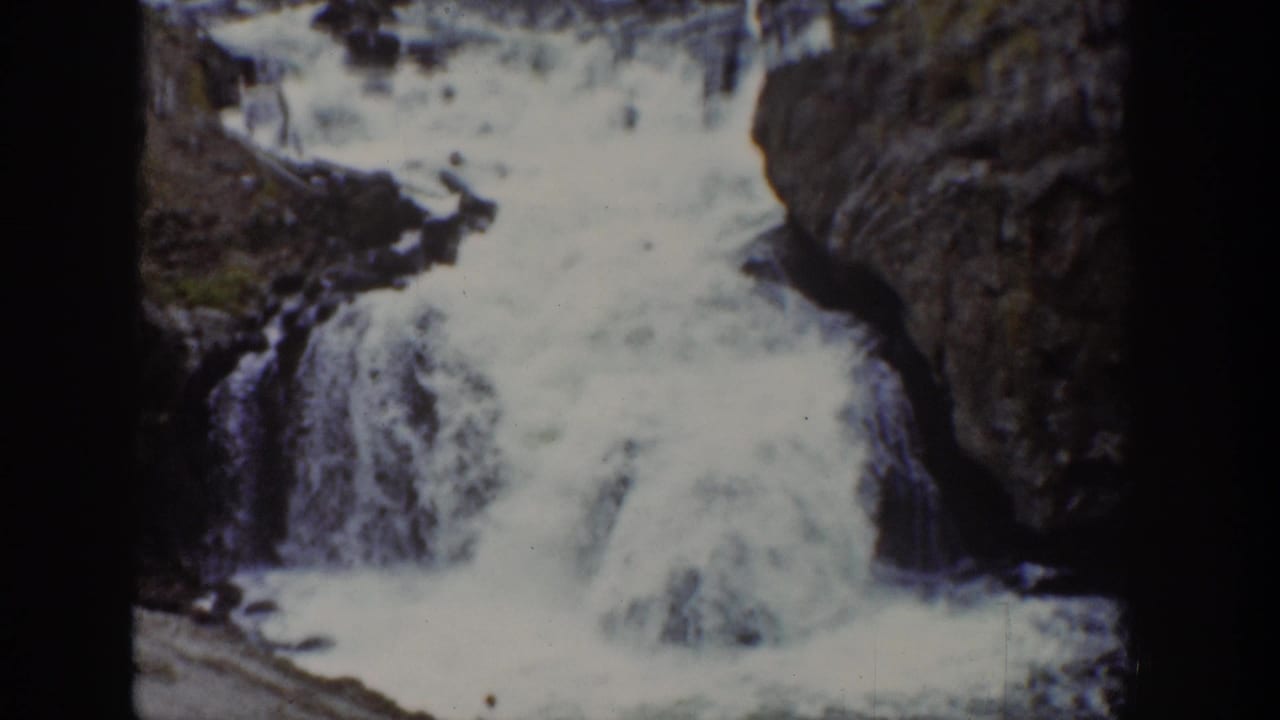 Closer view of a waterfall pouring over rocks into a canyon pool.