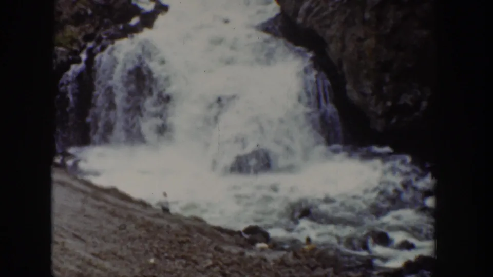1939 Wyoming 8mm view of the waterfall with a gravel foreground and small visitors visible near the lower edge.
