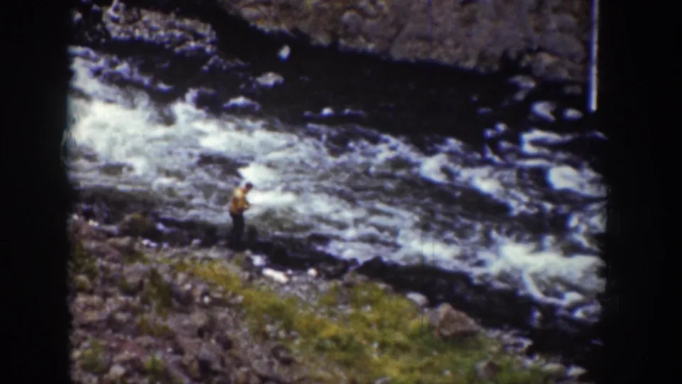 1939 Wyoming 8mm frame showing a man in a light shirt near fast water and a rocky mountain stream.