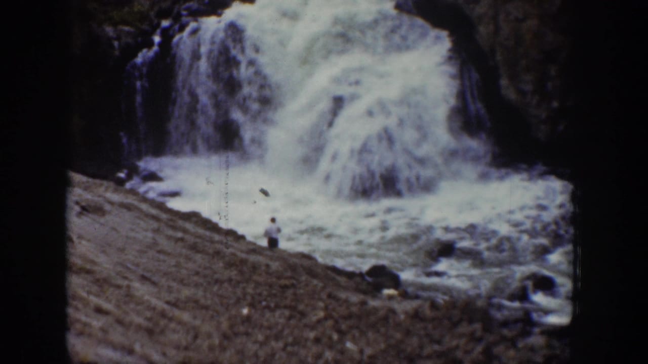 1939 Wyoming 8mm frame showing a distant person near a powerful waterfall and foaming riverbank.