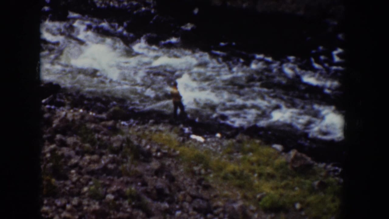1939 Wyoming 8mm frame with a person in a yellow top on a rocky riverbank beside whitewater.