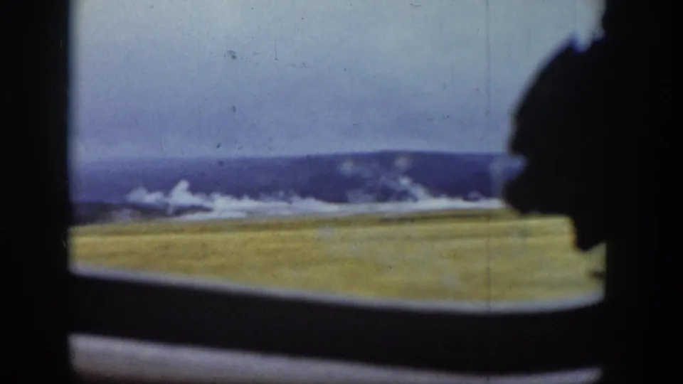 1939 Wyoming 8mm frame showing grassy plains and distant hills through a dark vehicle-window silhouette.
