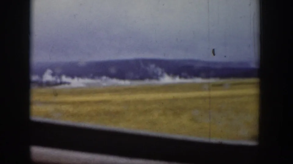 1939 Wyoming home-movie frame with grassland, distant hills, pale sky, and dark vehicle-window edge.