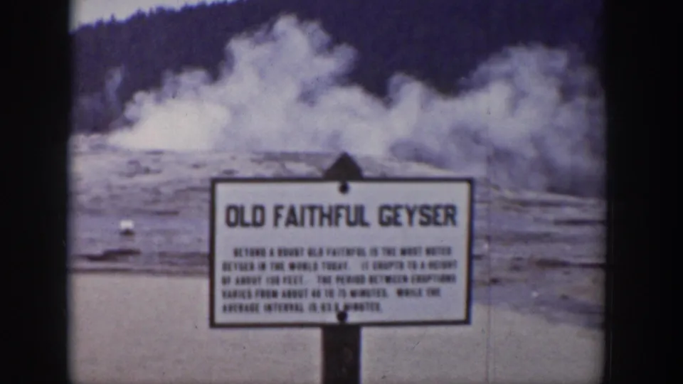 Old Faithful Geyser sign visible in a 1939 Yellowstone frame, with steam rising behind it.