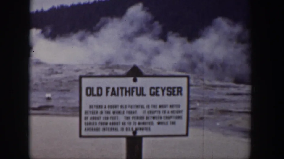 1939 Yellowstone home-movie frame with the Old Faithful Geyser sign and heavy steam in the background.