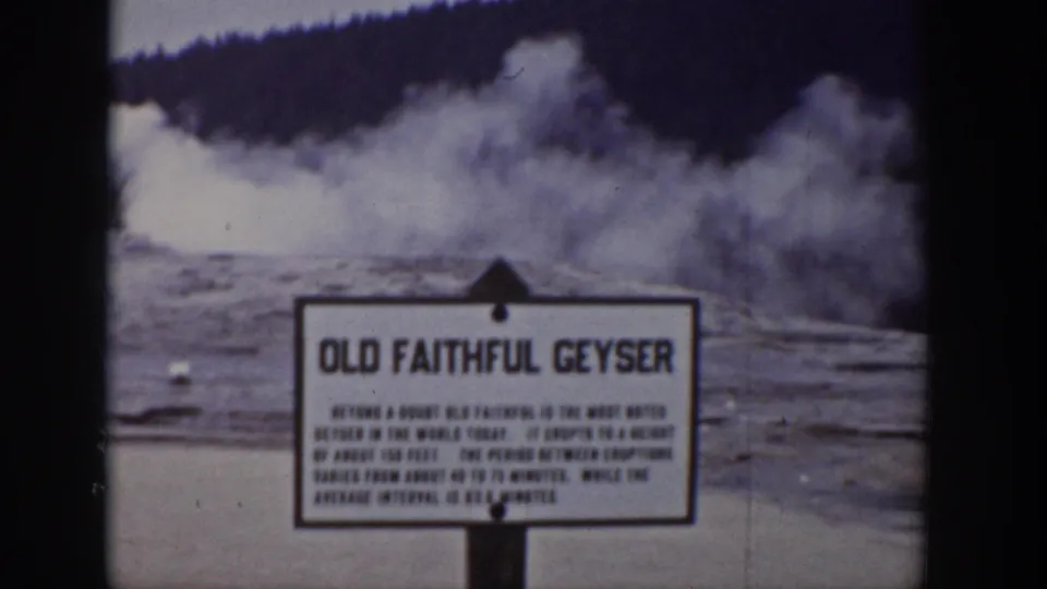 1939 Wyoming 8mm frame showing the Old Faithful Geyser sign with an eruption plume rising behind it.
