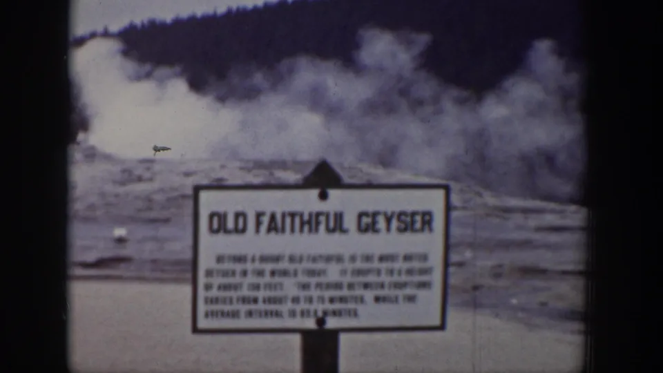 Faded 1939 Wyoming home-movie frame of the Old Faithful sign during a geyser eruption.