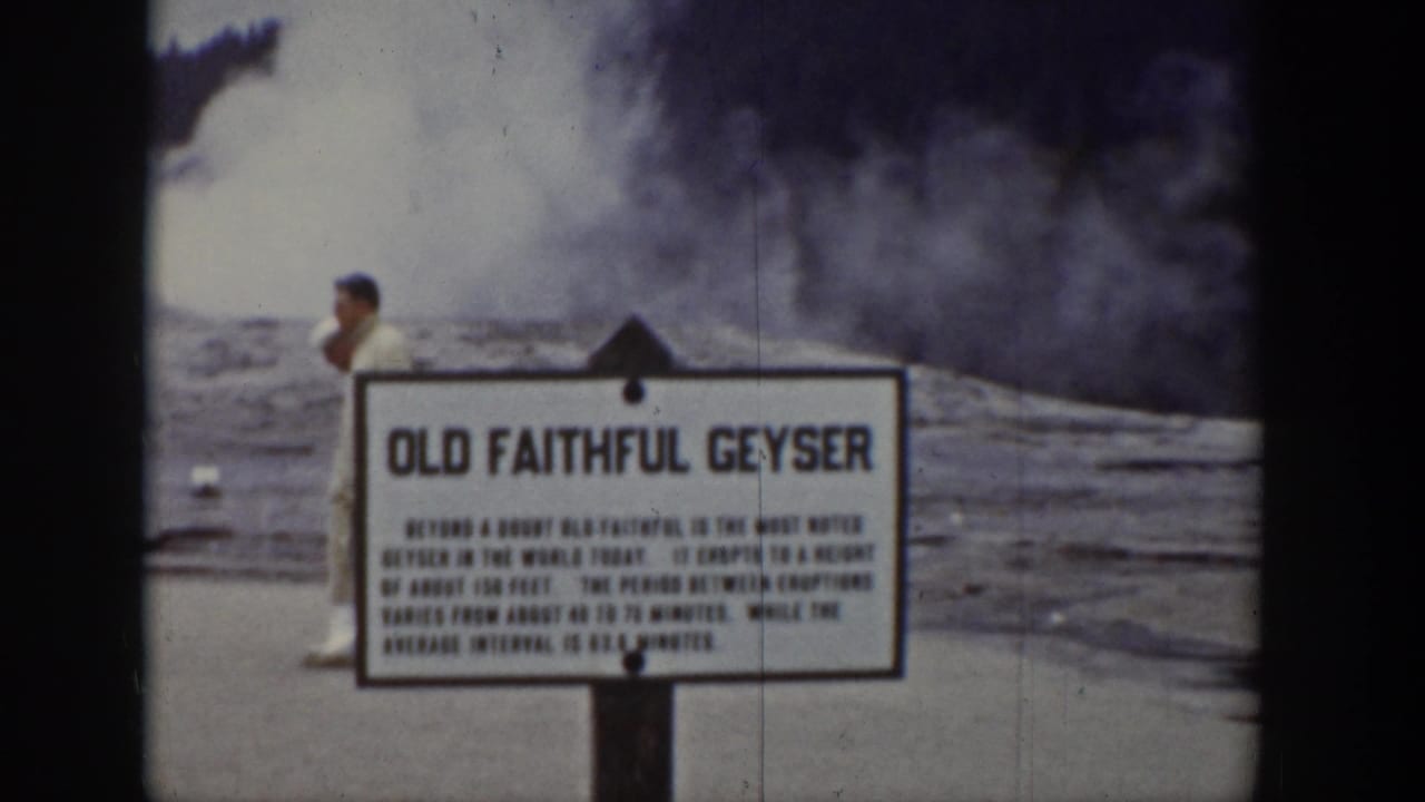 Old Faithful sign with a visitor behind it and steam rising across the basin.
