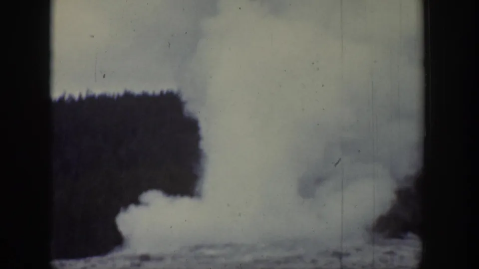1939 Wyoming frame with a geyser-like column of steam rising vertically against trees and sky.