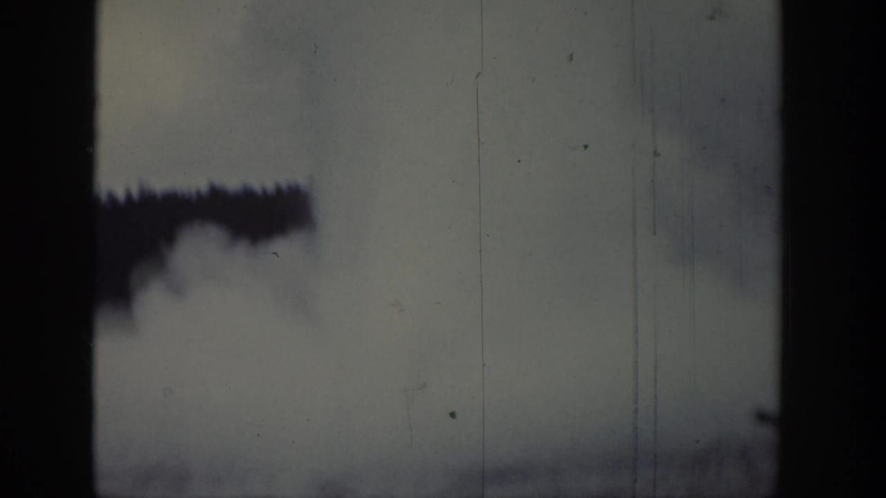 Dark vertical film edge with smoke-like plume against pale sky.