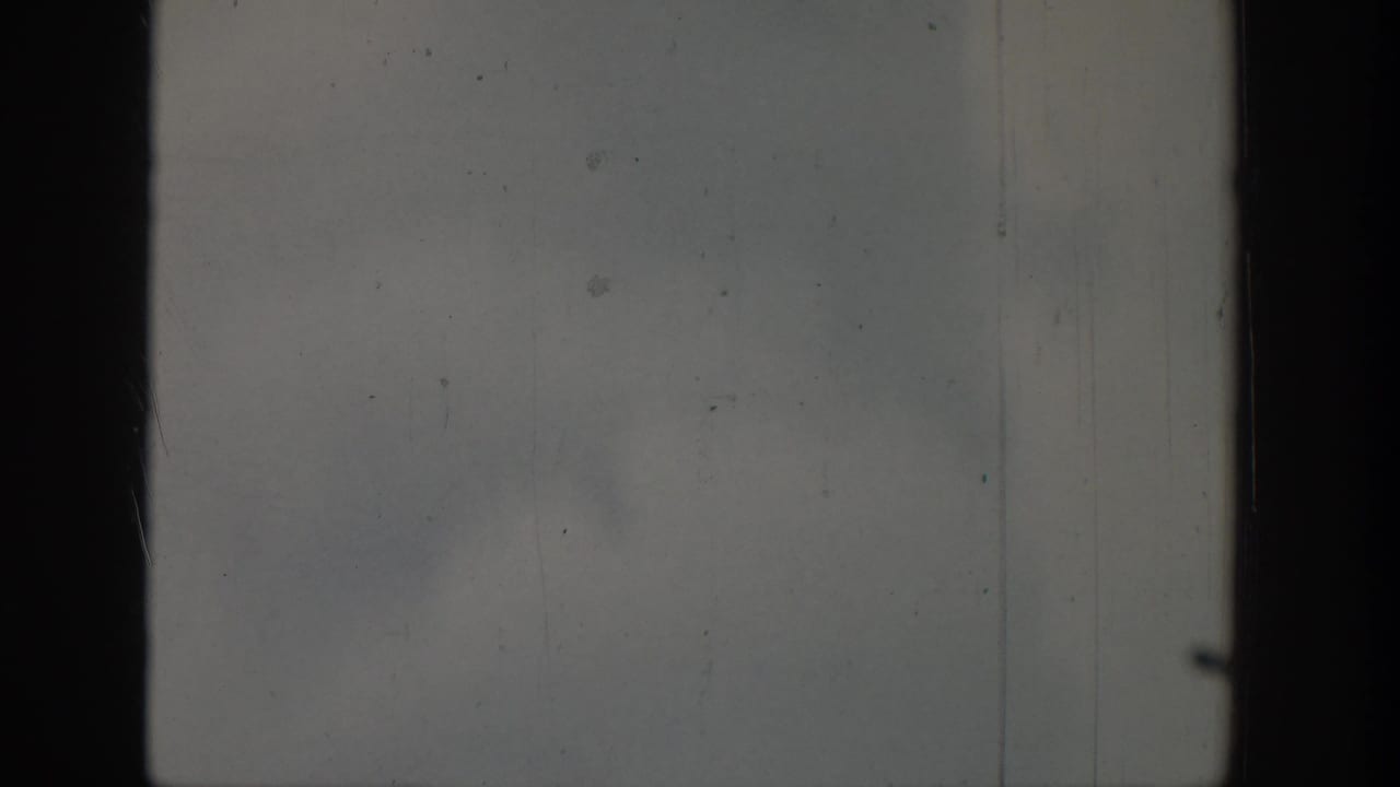 Pale scratched frame with a dark vertical band and faint cloudy or watery texture.