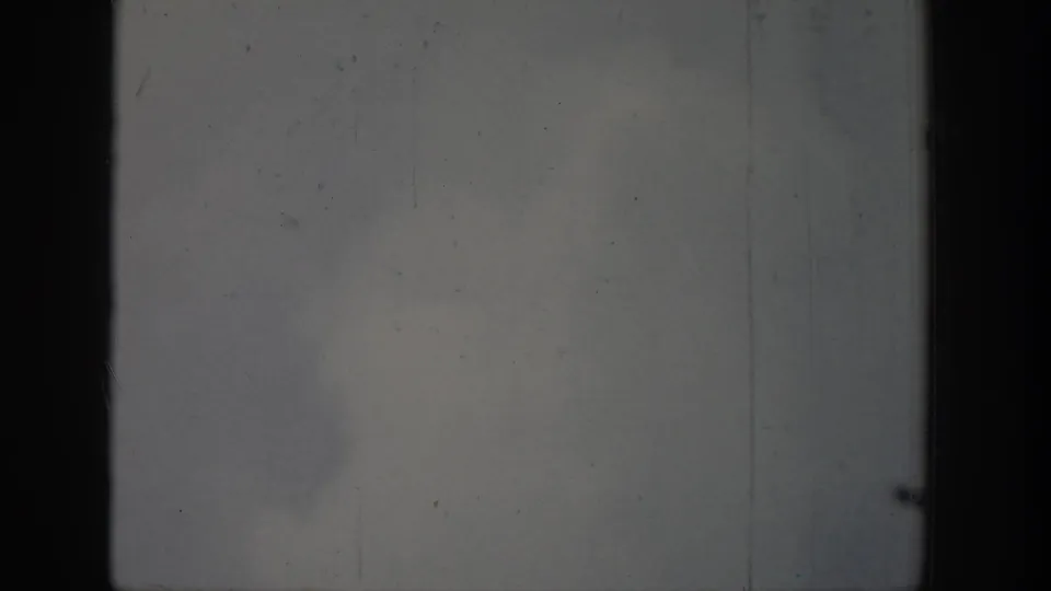 1939 Wyoming 8mm frame showing a faint geyser spray or steam plume rising against a cloudy sky with dark film borders.