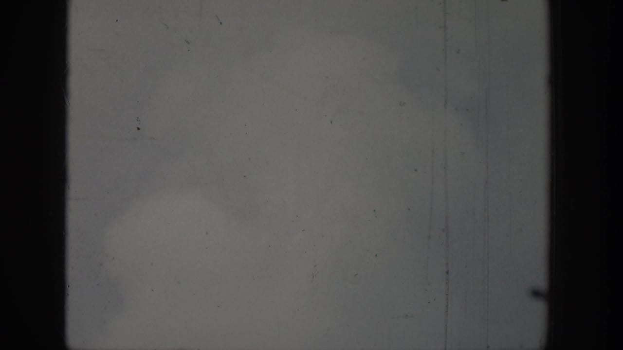 Cloudy sky framed by dark vertical film edges with little visible geyser spray.