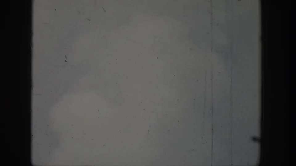 Black-and-white 8mm frame from the Wyoming geyser clip, dominated by cloudy sky and dark vertical film-frame borders.