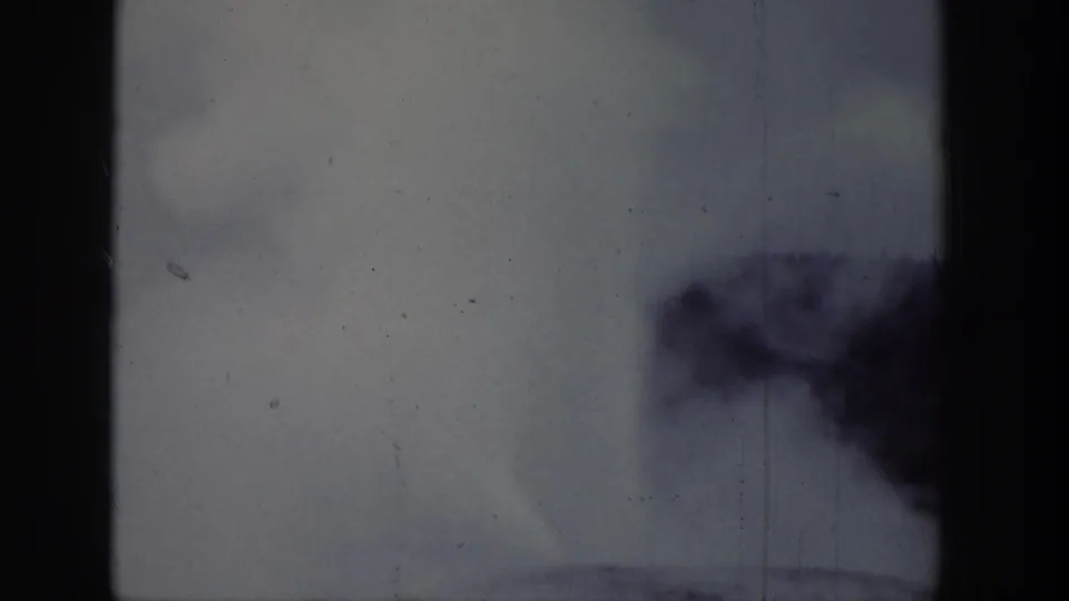1939 Wyoming 8mm frame with geyser spray and steam rising low in the frame, crossed by a dark film-frame edge.