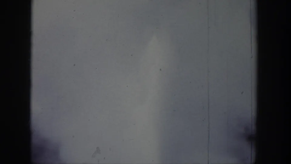 Pale clouds over a calm Wyoming waterside scene, recorded on 8mm film with dust, scratches, and dark edge framing.