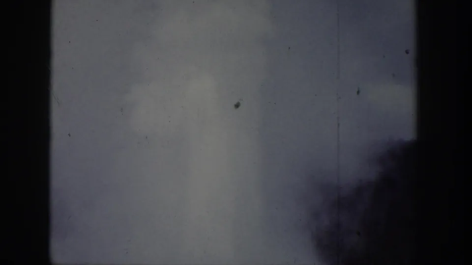 Wyoming-attributed 1939 home-movie frame with a pale plume partly obscured by dark tree or edge silhouettes.