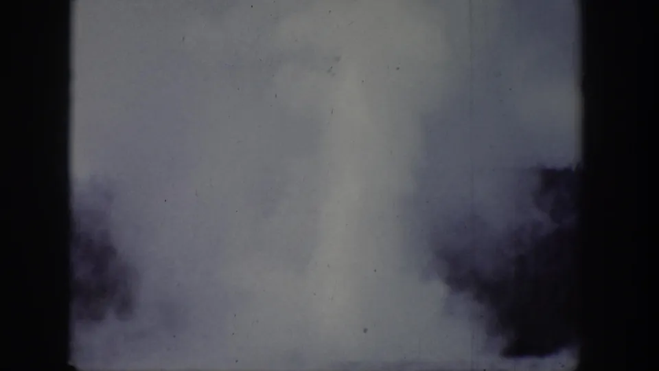 Wyoming-attributed 1939 frame with a tall pale plume rising near dark foliage and heavy edge shadowing.