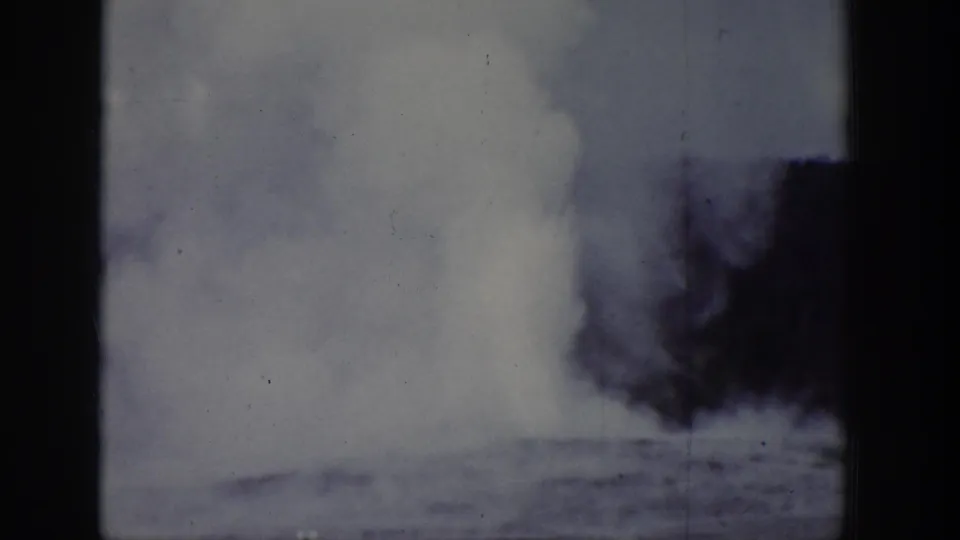 1939 Wyoming 8mm frame with a white geyser plume visible beyond a dark tree line and heavy frame-edge shadow.