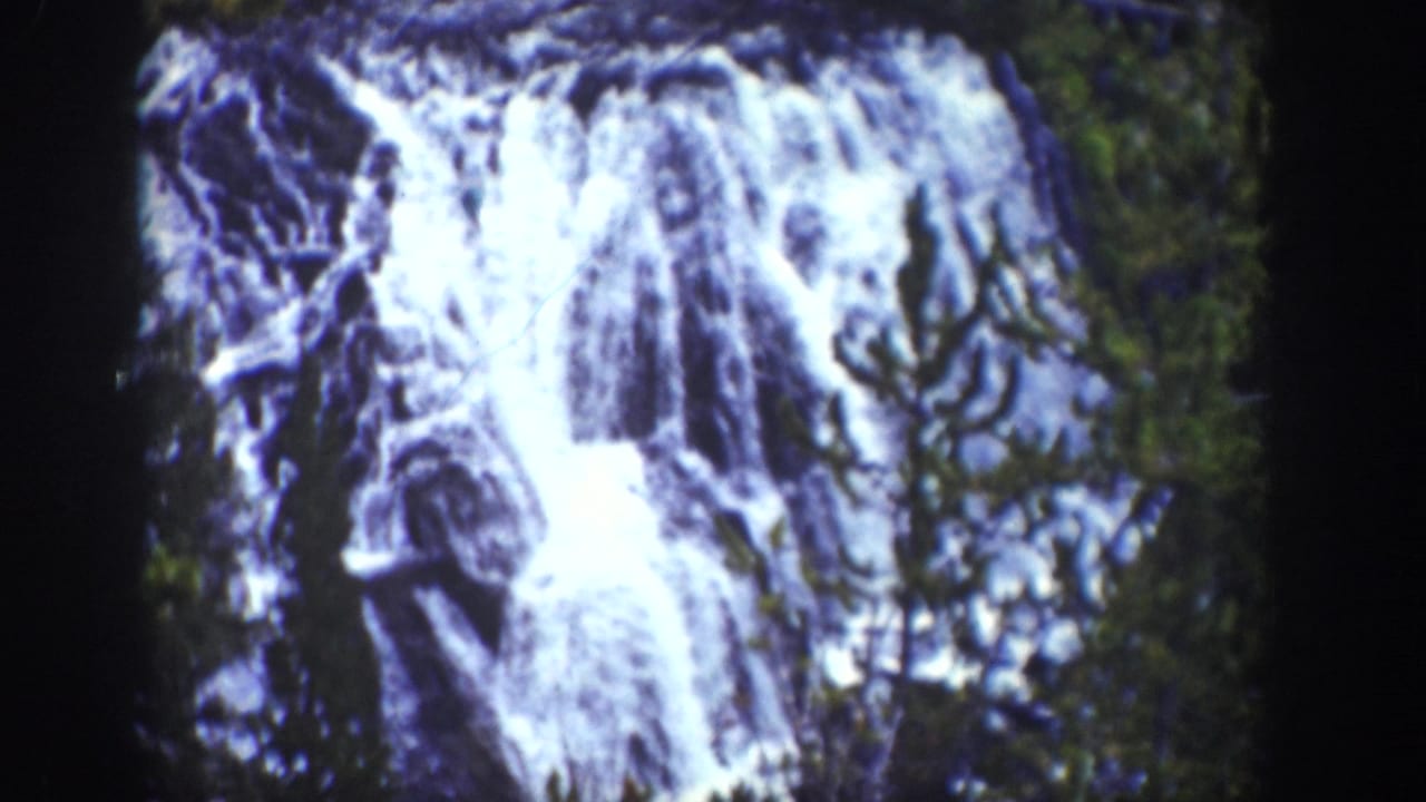 1939 Wyoming 8mm view of Kepler Cascades, with white water dropping over rocky ledges beside evergreen growth.