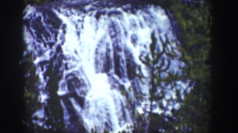 1939 Wyoming 8mm view of Kepler Cascades, with white water dropping over rocky ledges beside evergreen growth.