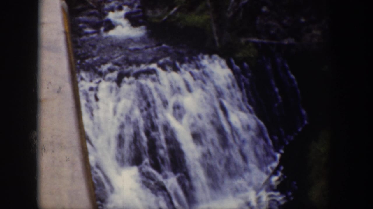 1939 Wyoming 8mm frame showing rushing stream water over rocks in a forested valley.