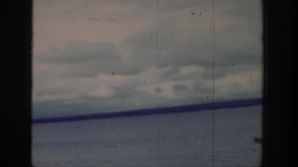 Soft 8mm view of a Wyoming lake, showing gray-blue water, low clouds, and land across the horizon.