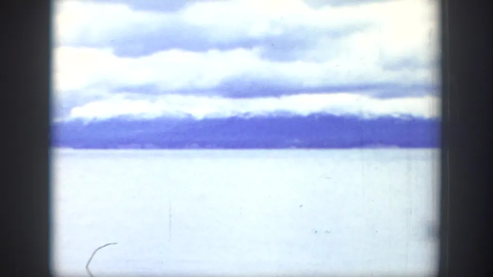 A lake and distant mountain range appear under heavy clouds in the Wyoming travel footage.