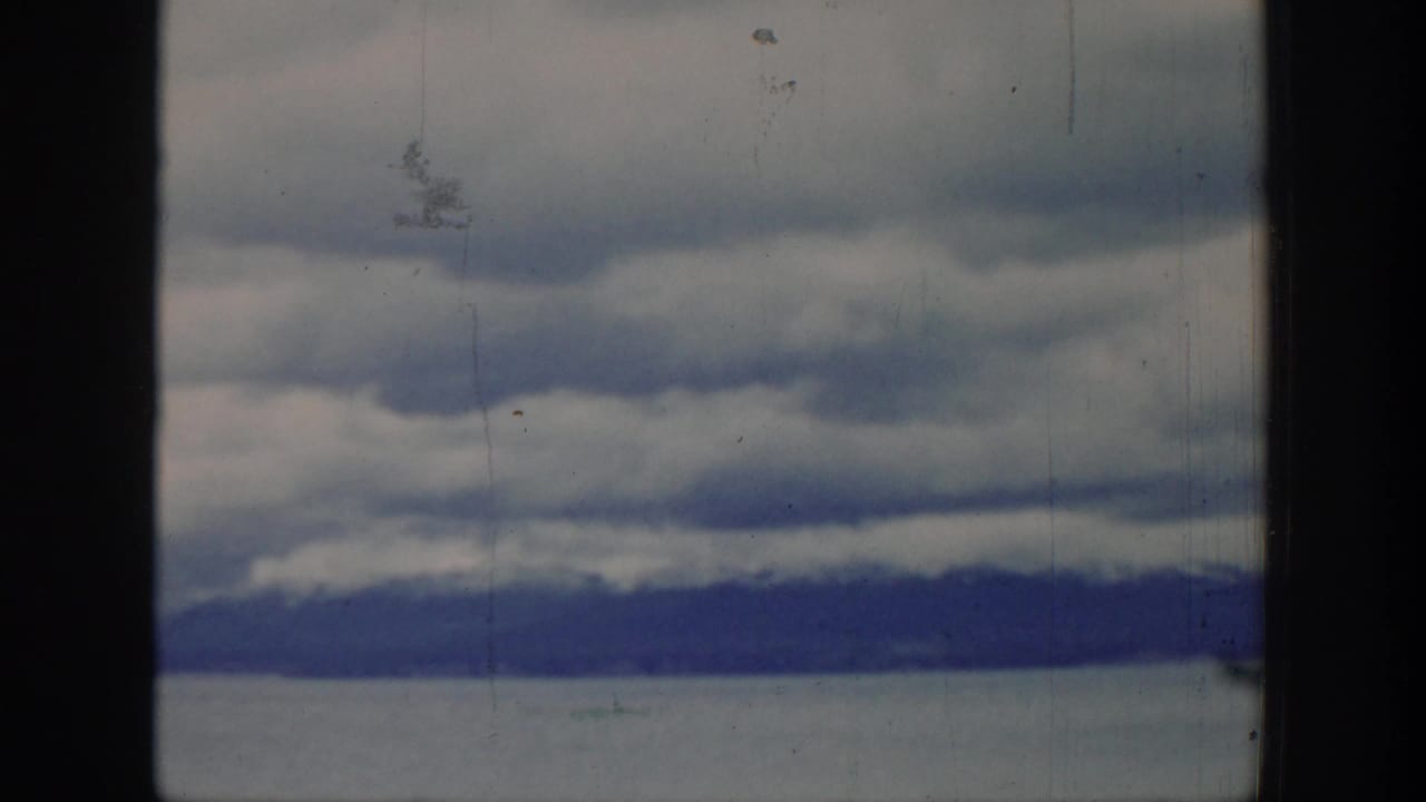 Distant mountains beneath layered clouds in a soft 8mm frame.
